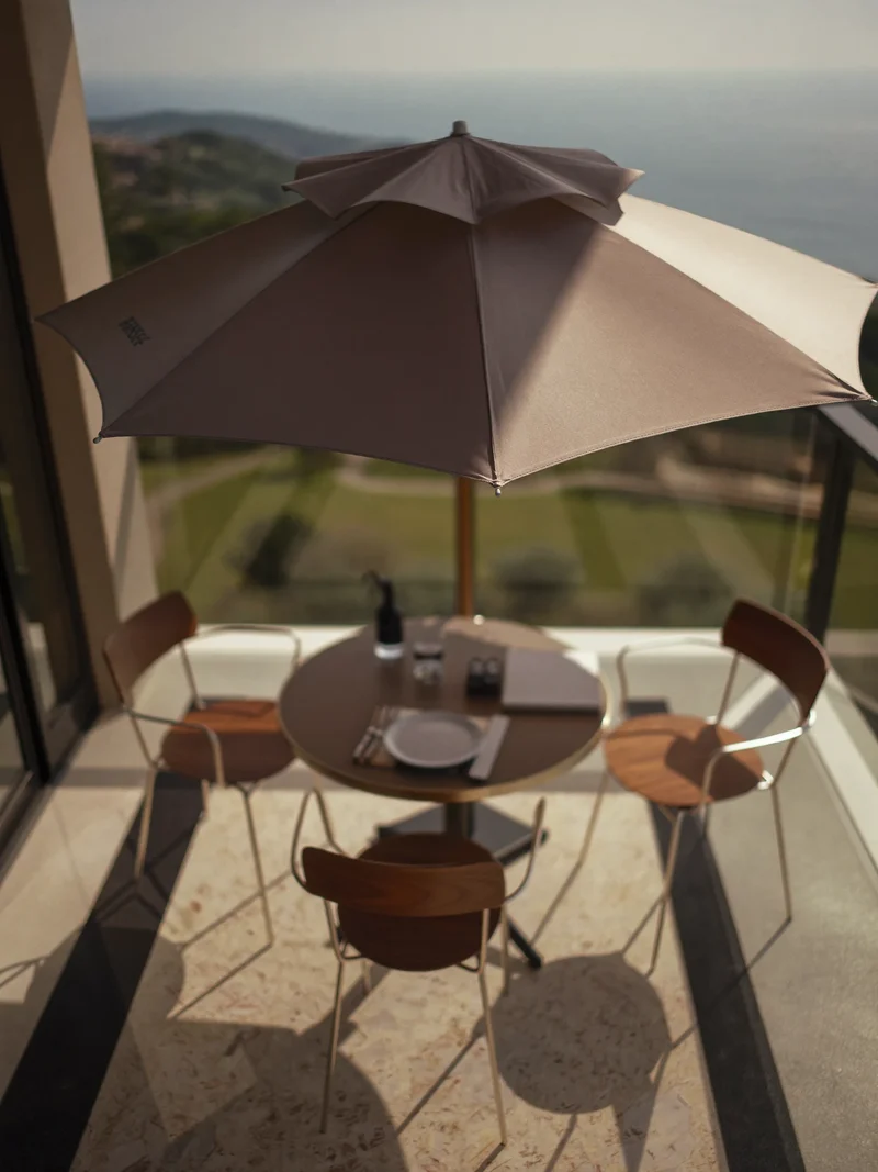 Ampelschirm über einem kleinen Bistrotisch mit zwei Stühlen auf einem Balkon